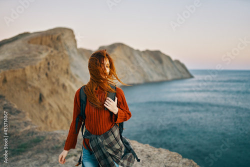 romantic traveler with backpack in the mountains in nature sunset and sea in the background