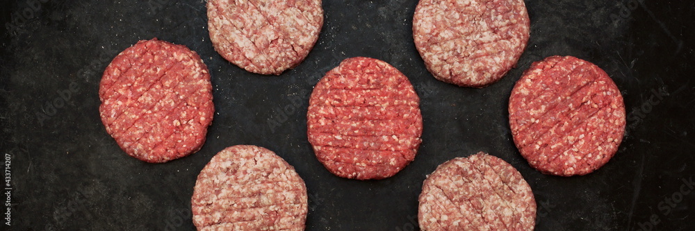 Raw Minced Steak Burgers from Beef and Pork Meat on Black Background, Overhead View. Raw Ground Beef, Round Patties for Cooking Homemade Burger On BBQ Grill, Top View Raw Minced Steak Burgers from Beef and Pork Meat on Black Background, Overhead View. Raw Ground Beef, Round Patties for Cooking Homemade Burger On BBQ Grill, Top View