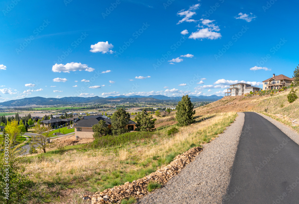 View from a concrete hiking path on the top of a hill in Liberty Lake, with new luxury homes being built overlooking the Spokane Valley, Newman Lake, Washington cities.