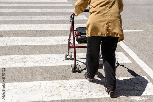 Rollator pushed by an elderly woman with mobility difficulties, unrecognizable with copy space.