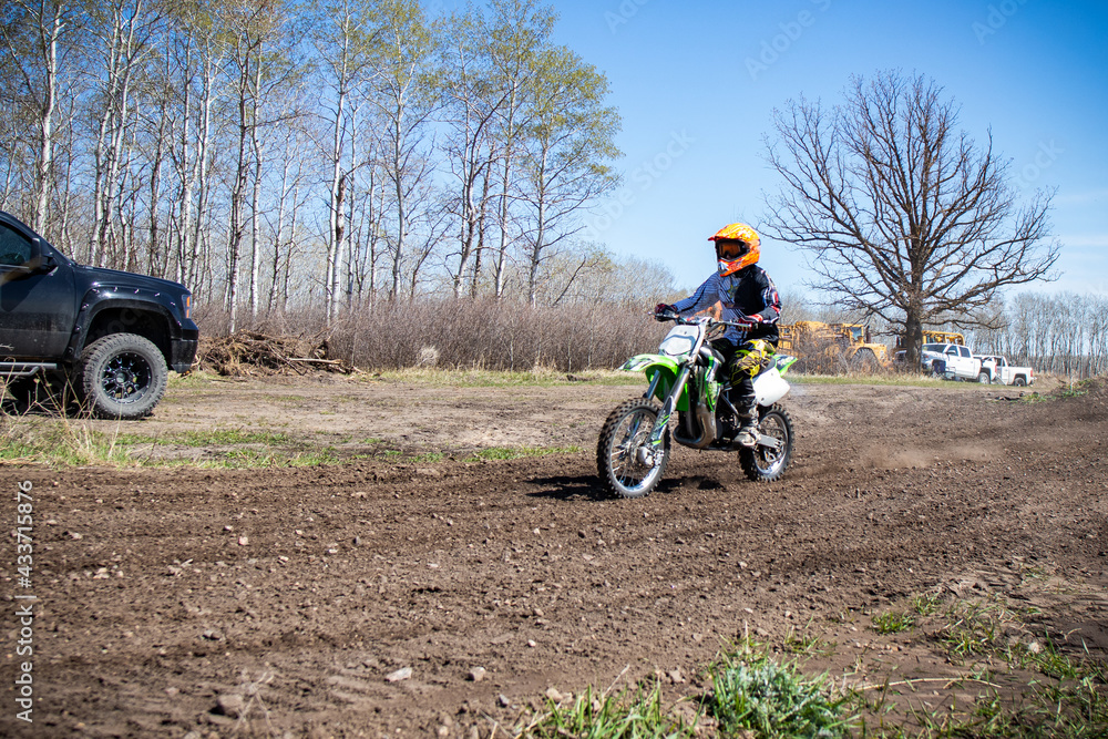 A kid rides his dirt bike on an out door track. A kid rides his dirt bike on an out door track.