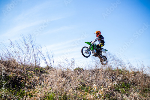 A kid jumps his dirt bike on an out door track.