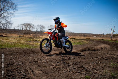Dirt biker does a wheelie as he comes out of a corner.