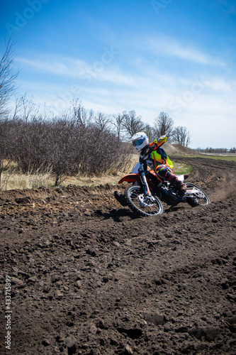 Fototapeta Naklejka Na Ścianę i Meble -  Motocross rider rides an orange dirt bike on a race track.