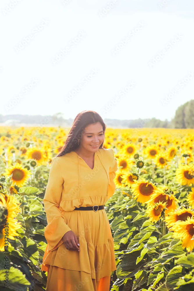 A brunette woman in a yellow dress on the field with sunflowers. Orange dress. A brunette woman in a yellow dress on the field with sunflowers. Orange dress.