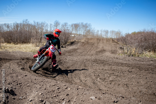 Dirt bike rider enters a corner after landing a jump on a motocross track.