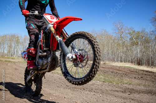 Close up of a motorcycle as it does a wheelie on a dirt track.