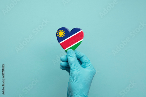 Hands wearing protective surgical gloves holding Namibia flag heart