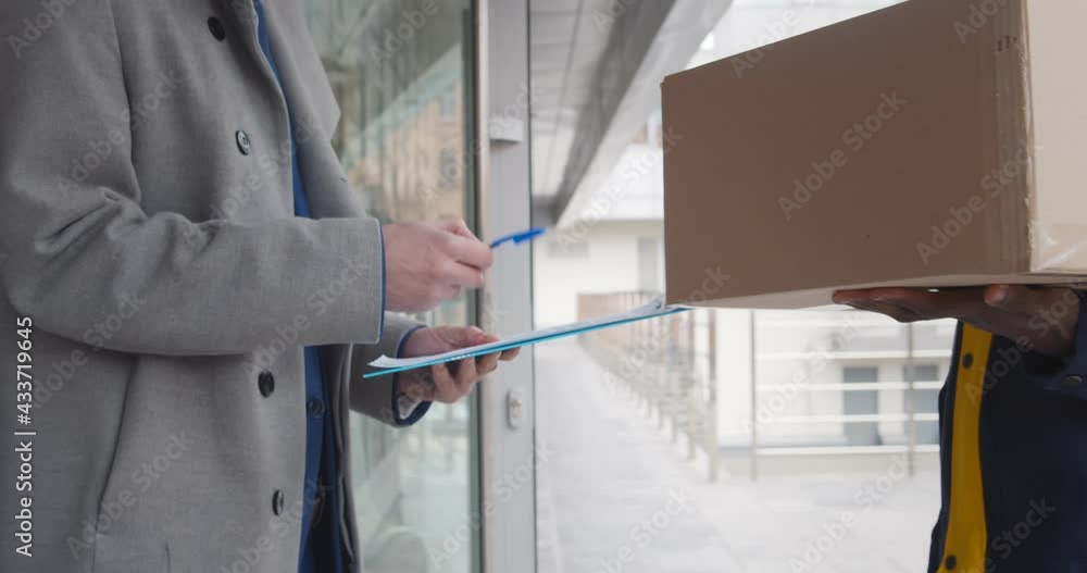 Cropped shot of man customer signing in clipboard form to receive package Cropped shot of man customer signing in clipboard form to receive package
