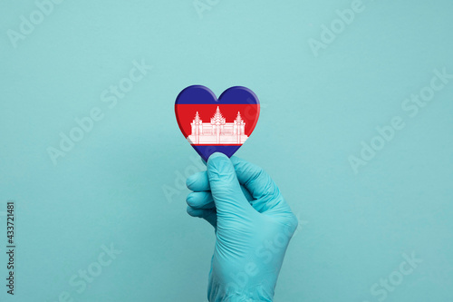 Hands wearing protective surgical gloves holding Cambodia flag heart