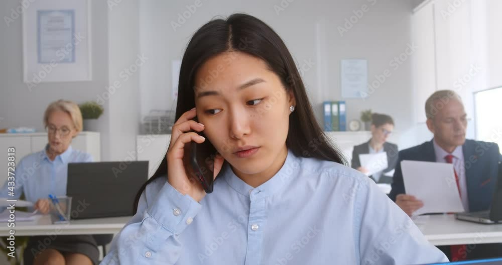 Asian young woman sitting at desk working and answering phone call Asian young woman sitting at desk working and answering phone call