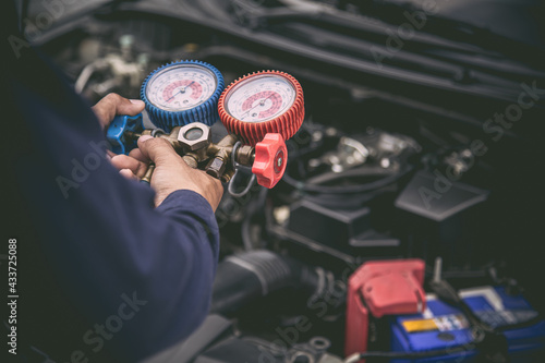 Close up hand auto mechanic use measuring manifold gauge for filling car air conditioners. Concepts of fix and checking for repair service and car maintenance and insurance.