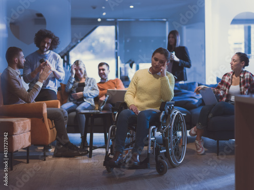Portrait of disabled businesswoman in a wheelchair in front of her diverse business team at office