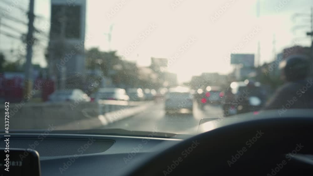 Handheld shot on driving in bad traffic after office hour, on the way home. POV front mirror inside moving car along the cement barrier and other vehicles in rush hour, lens flare on steering wheel Handheld shot on driving in bad traffic after office hour, on the way home. POV front mirror inside moving car along the cement barrier and other vehicles in rush hour, lens flare on steering wheel