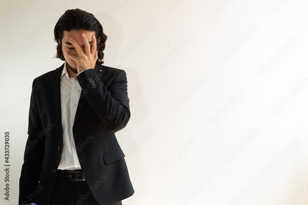 Hispanic man with long hair and a black suit frustrated on a white background Hispanic man with long hair and a black suit frustrated on a white background