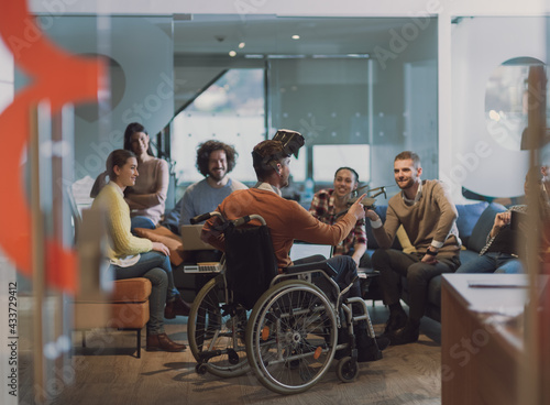 Disabled businessman in a wheelchair at work in modern open space coworking office with team using virtual reality googles drone assistance simulation photo