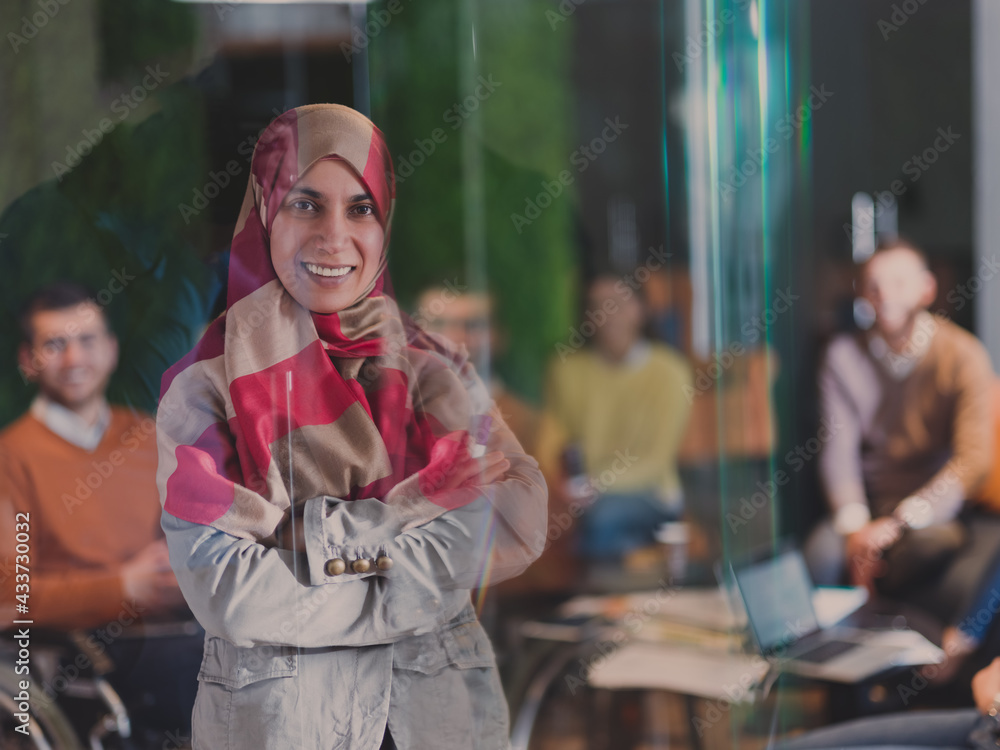 Fototapeta premium Muslim woman wearing hijab in office, Arabic business woman covered with headscarf smiling. Successful Arab businesswoman in modern office.