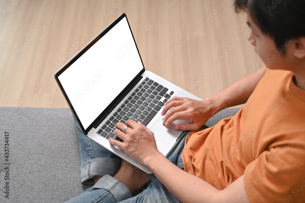Side view casual man freelancer working with laptop while sitting on sofa. Side view casual man freelancer working with laptop while sitting on sofa.