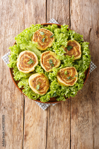 Fleischschnacka snails of meat, this French recipe from the Alsace serve with green salad close-up in a plate on the table. Vertical top view from above