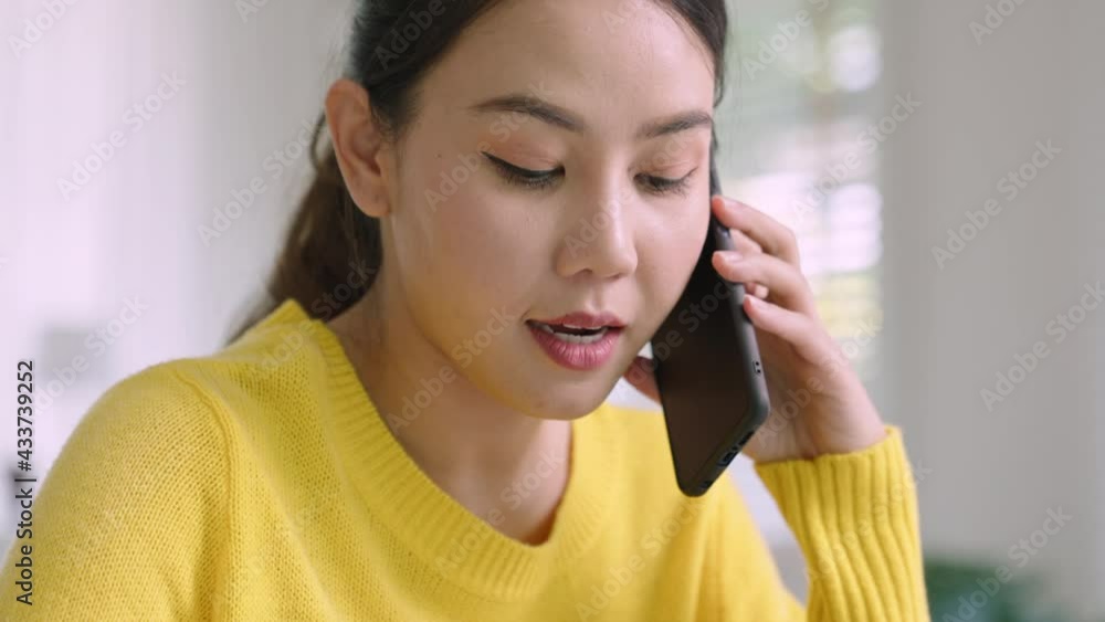 Young happy attractive beautiful asia female staff laugh talk on mobile phone relax comfort sit work on desk table at home. Remotely work on distance job telesale or secretary career for business. Young happy attractive beautiful asia female staff laugh talk on mobile phone relax comfort sit work on desk table at home. Remotely work on distance job telesale or secretary career for business.