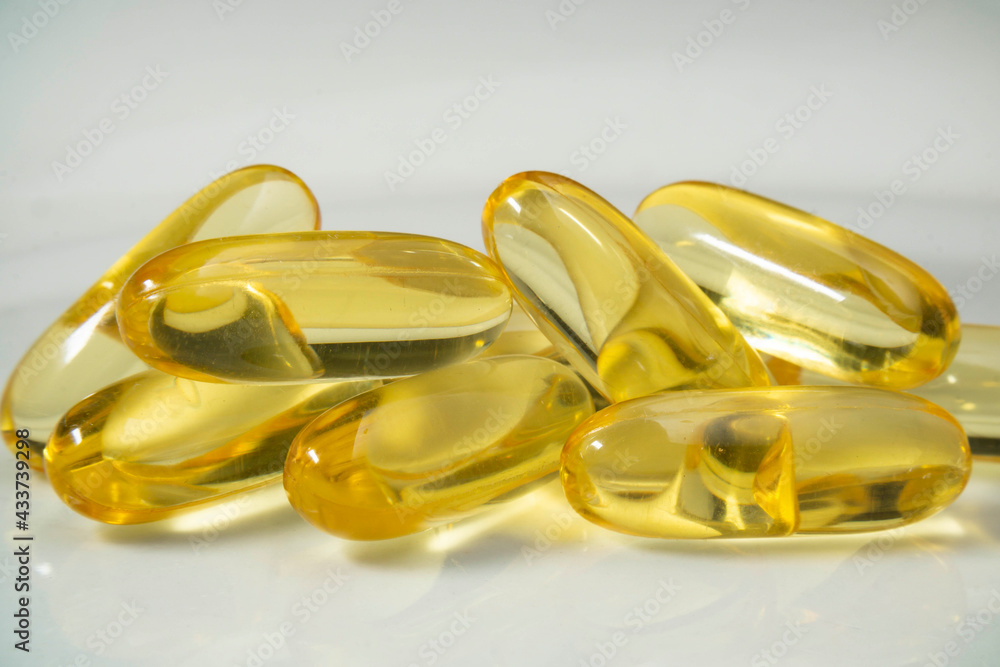 Cod oil fish oil capsule pill stack together. Close up fish oil pills on the white plate Cod oil fish oil capsule pill stack together. Close up fish oil pills on the white plate