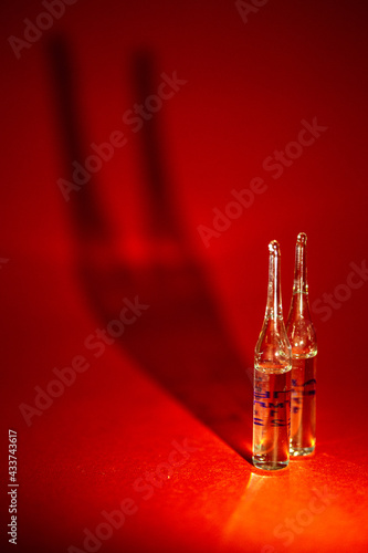 two vials with a drug against the virus on a red background with a shadow