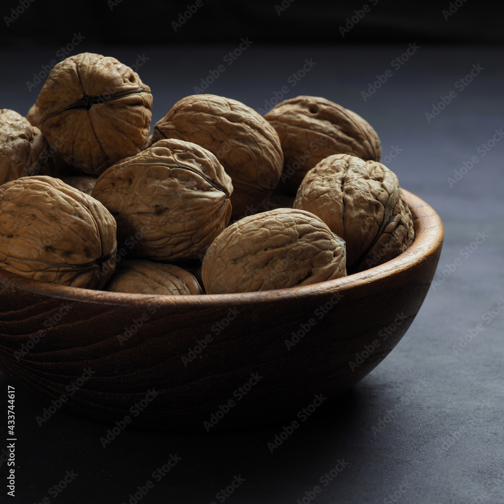 Walnuts in a wooden bowl on a dark background. Walnuts in a wooden bowl on a dark background.