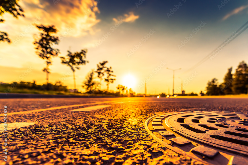 Sunset in the country, the empty highway. Wide angle view of the level of a manhole on the pavement