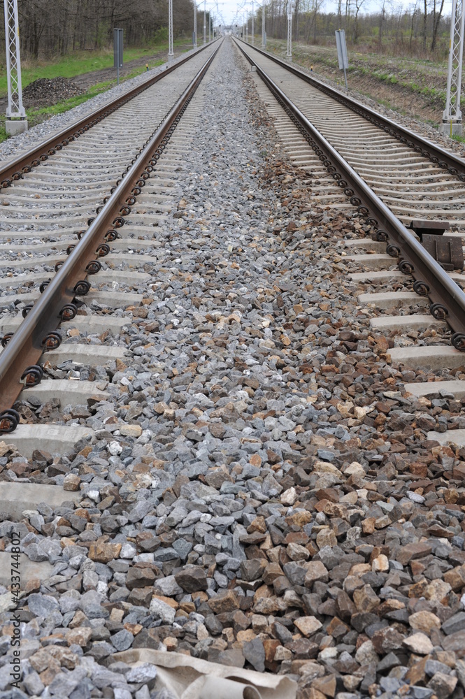 Railroad tracks for trains with steel rails and gravel creating straight perspective lines till horizon Railroad tracks for trains with steel rails and gravel creating straight perspective lines till horizon