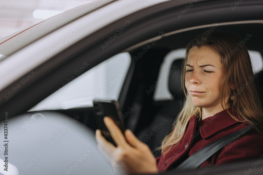 Puzzled woman reading a text message while sitting in the car. Puzzled woman reading a text message while sitting in the car.