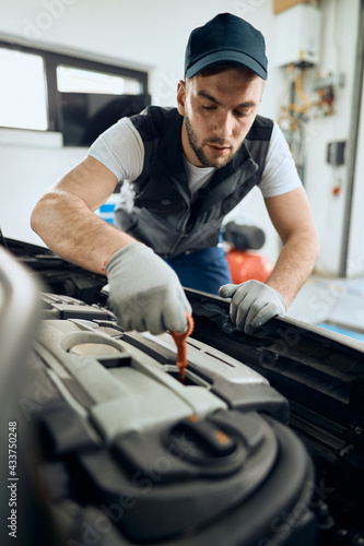 Auto repairman examining car oil while working in a repair shop.