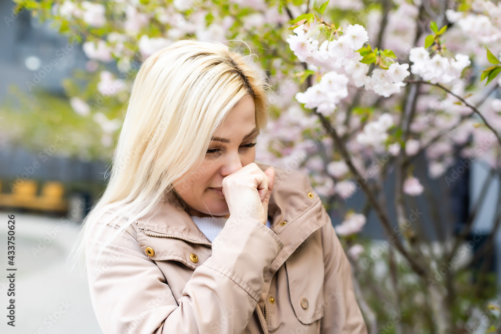 Young pretty girl blowing nose in front of blooming tree. Spring allergy concept Young pretty girl blowing nose in front of blooming tree. Spring allergy concept