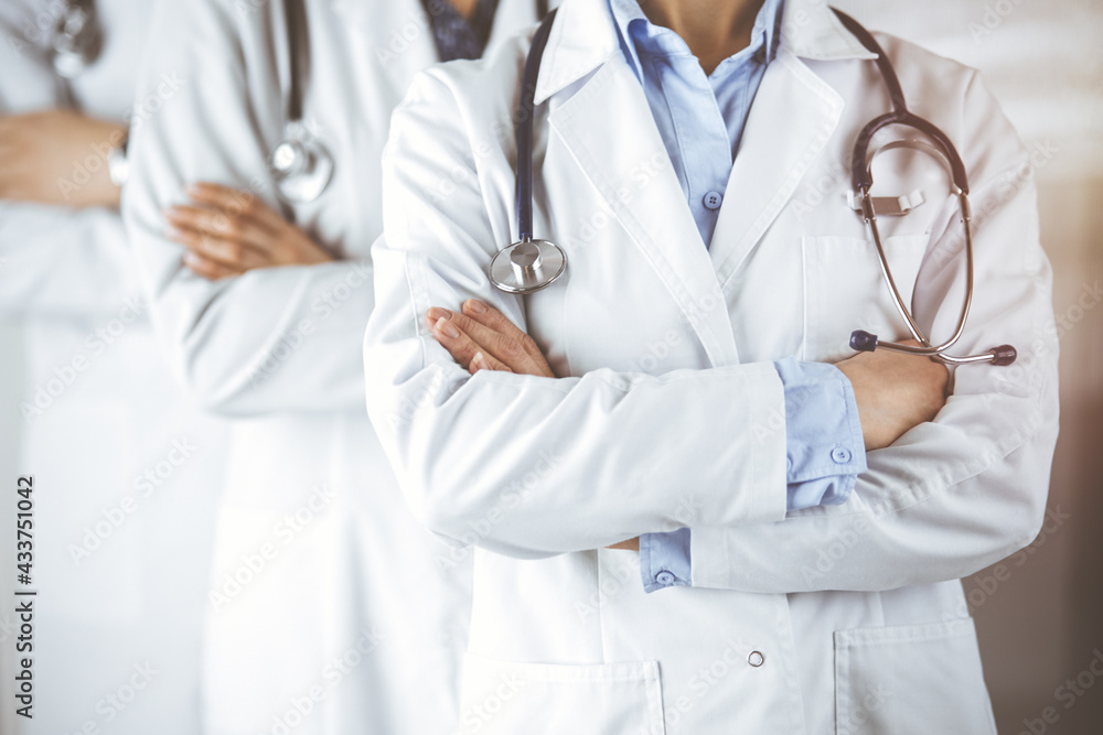 Group of modern doctors standing as a team with arms crossed in sunny hospital and ready to help patients. Medical help, insurance in health care