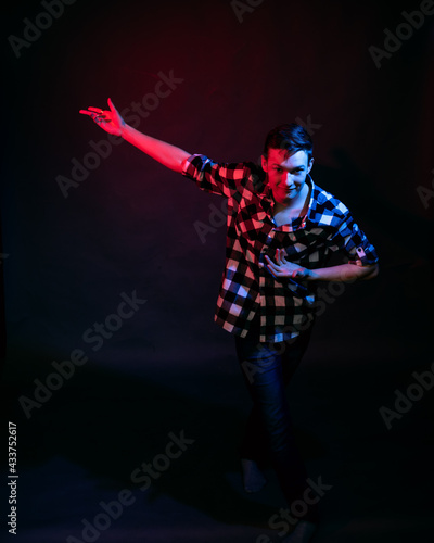 A young man in a studio on a dark background with a multicolored light