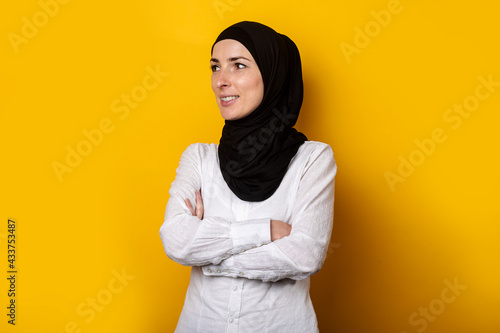 Young cheerful muslim woman in hijab on a yellow background. Banner © Alex