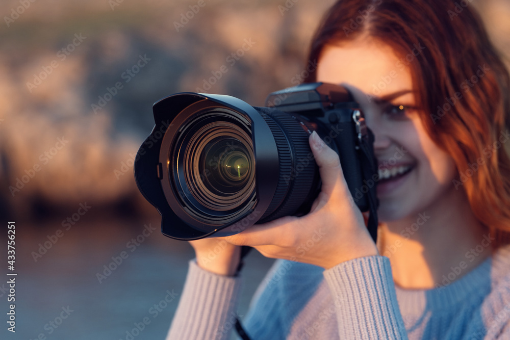 beautiful red-haired woman with a camera on nature in the mountains near the river beautiful red-haired woman with a camera on nature in the mountains near the river