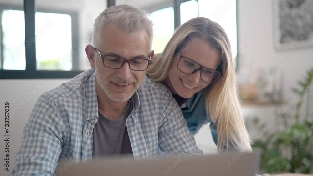 Couple with eyeglasses connected with laptop computer at home Couple with eyeglasses connected with laptop computer at home