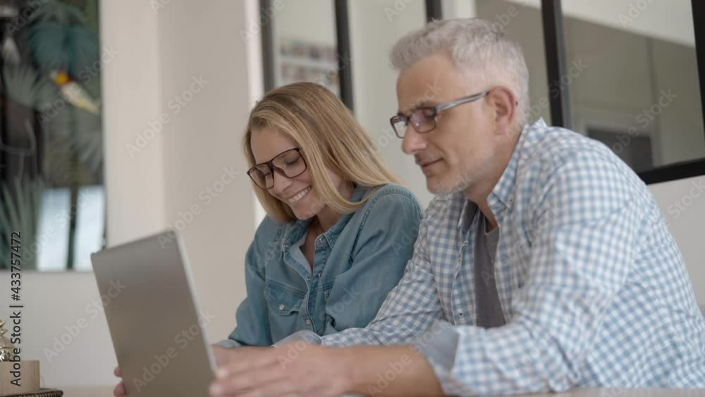 Couple with eyeglasses connected with laptop computer at home Couple with eyeglasses connected with laptop computer at home