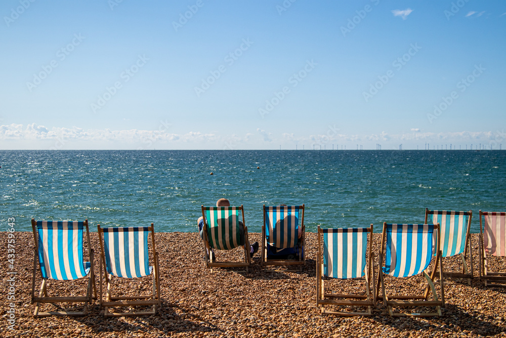 A couple relaxing on the striped chairs in Brighton beach, England A couple relaxing on the striped chairs in Brighton beach, England