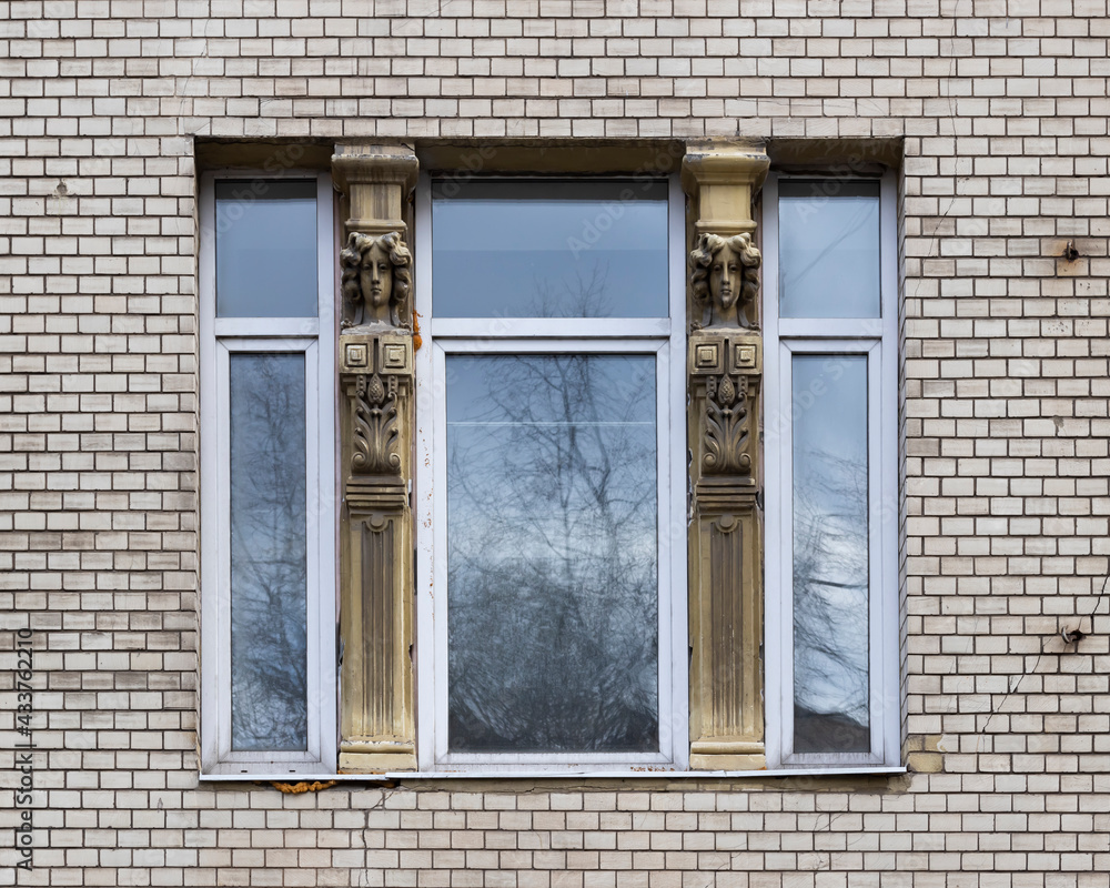 Vintage architecture classical facade in Art Nouveau style front view. One window modern plastic frame historical columns with female heads