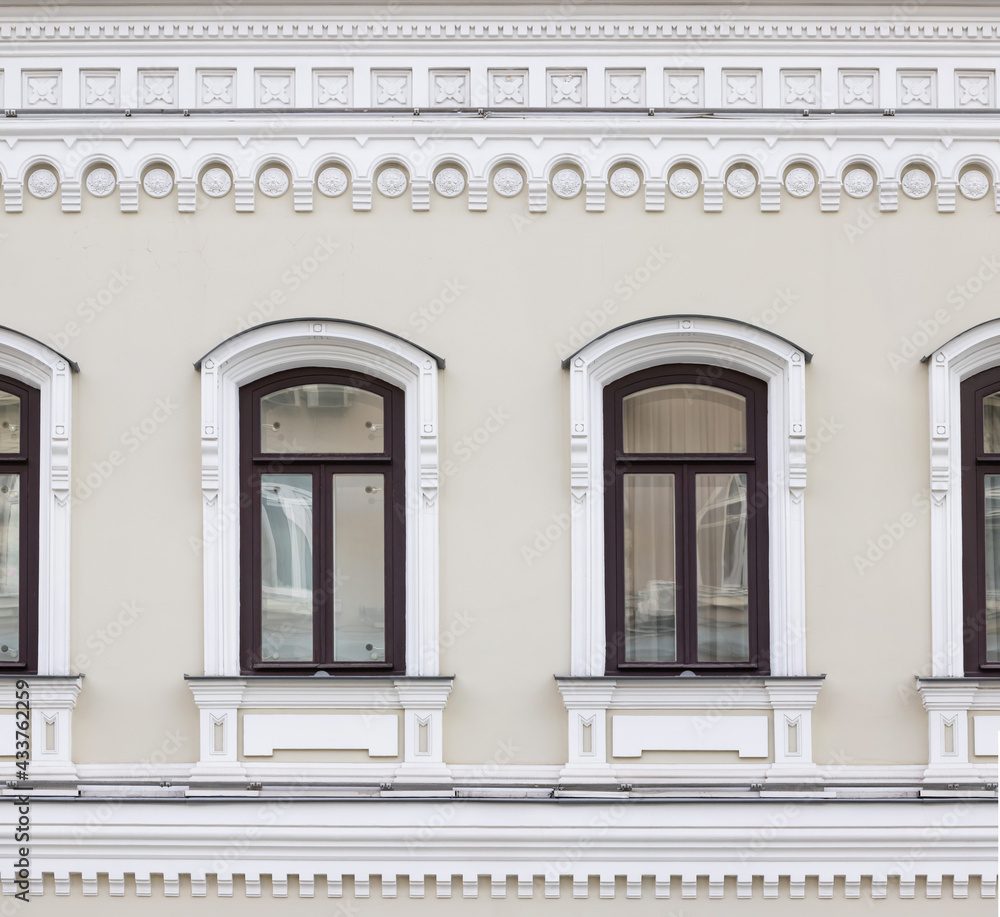 Vintage architecture classical facade building. Windows framed in architectural  Russian style decor. Front view.