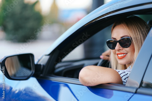 Confident and beautiful woman in sunglasses. Rear view of attractive young female in casual wear driving a car