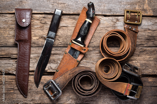 Tablou pe pânză Hunting knives, leather belts and sheaths on the old wooden table background