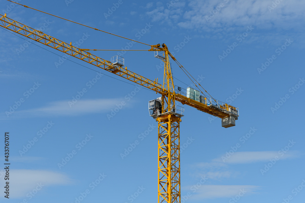 Construction tower crane with cab on blue sky background Construction tower crane with cab on blue sky background