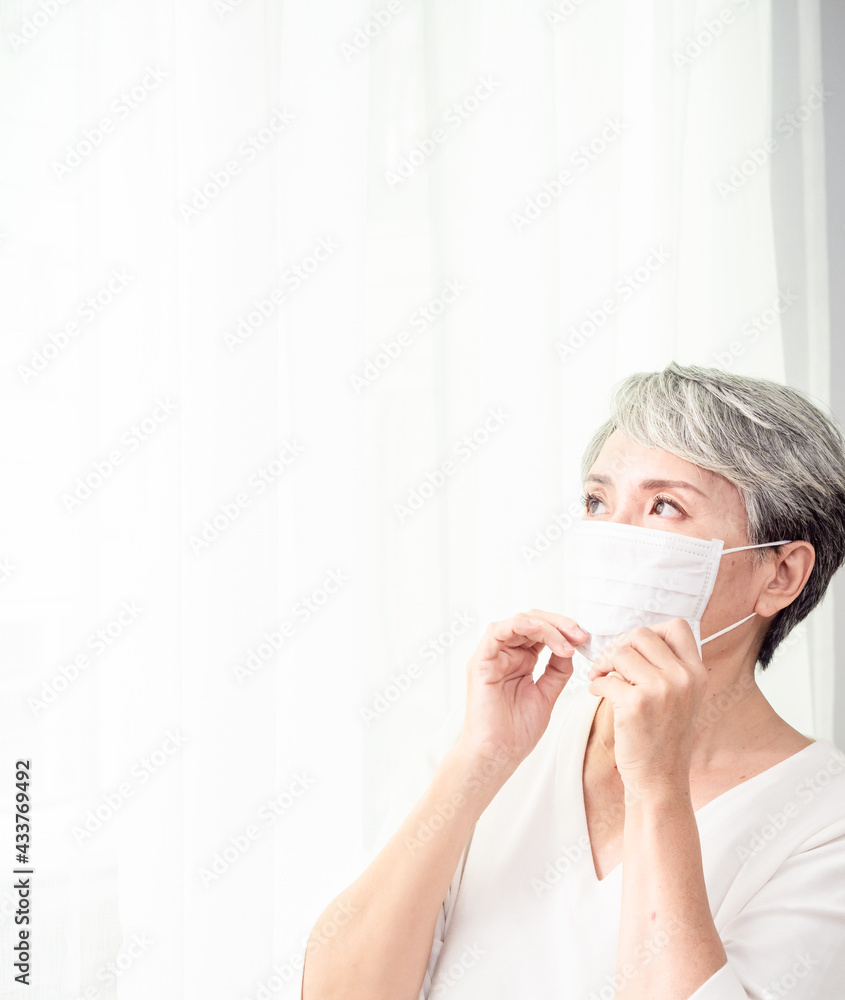 Senior asian woman wearing facemask during coronavirus and flu outbreak. Virus and illness protection, home quarantine. COVID-19. Taking on or taking off masks. Senior asian woman wearing facemask during coronavirus and flu outbreak. Virus and illness protection, home quarantine. COVID-19. Taking on or taking off masks.