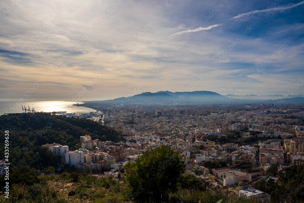 Beautiful landscape of European city next to the port and the mountain at sunset. Malaga city next to the Mediterranean Sea.