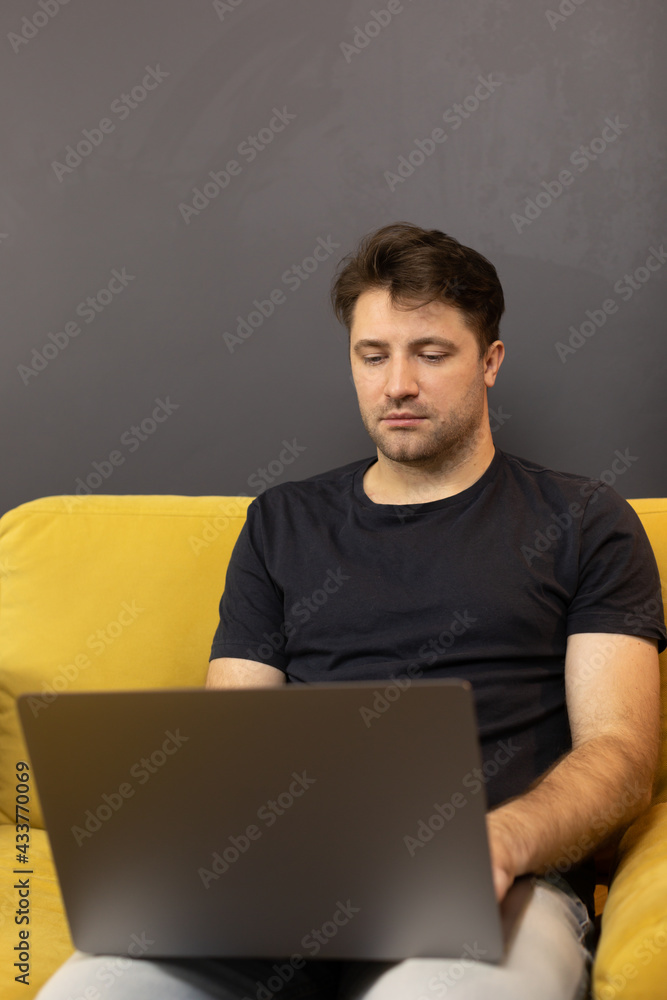 focused web designer working from home distantly, sitting on sofa with laptop computer, handsome guy staying connected during pandemic Lockdown communicating on social networks copy space focused web designer working from home distantly, sitting on sofa with laptop computer, handsome guy staying connected during pandemic Lockdown communicating on social networks copy space
