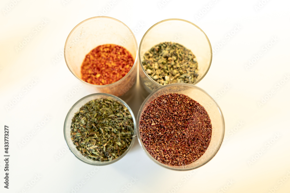 Spices in glass jars. Sumar, chili peppers, thyme and mint. Turkish food spices. Selective focus, top view. Spices in glass jars. Sumar, chili peppers, thyme and mint. Turkish food spices. Selective focus, top view.