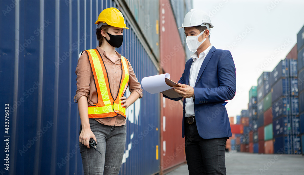 asian businessman using clipboard and harbor worker woman wareing face mask checking list inventory loading Containers box at warehouse logistic in Cargo during coronavirus, covid 19 pandemic asian businessman using clipboard and harbor worker woman wareing face mask checking list inventory loading Containers box at warehouse logistic in Cargo during coronavirus, covid 19 pandemic
