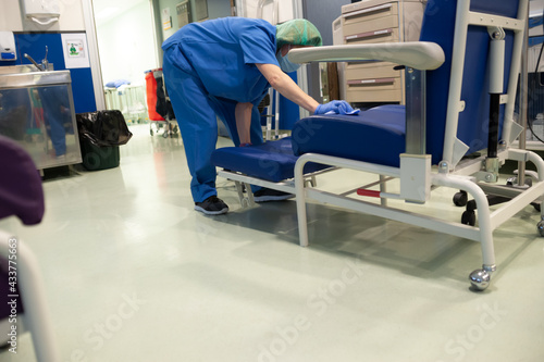 Konstfotografi Woman from the cleaning service of a hospital cleaning an extended sofa of the patients in the previous operating room